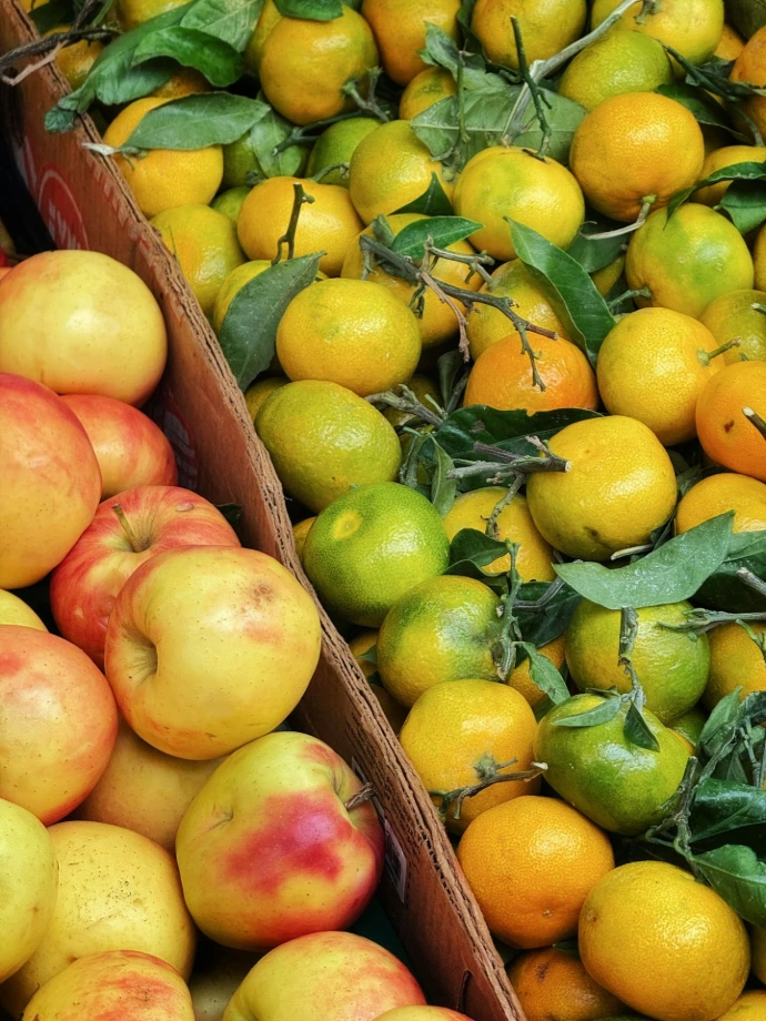 Fresh apples and tangerines with leaves in boxes